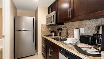 A modern kitchen with stainless steel appliances, granite countertops, and dark wooden cabinets.