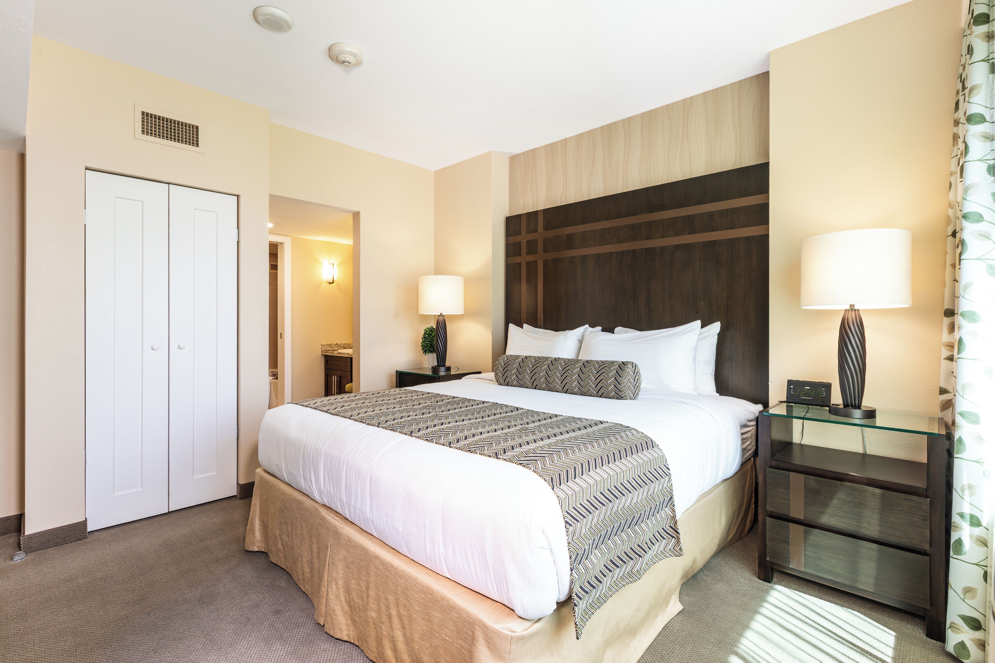 Ein Hotelzimmer mit einem großen Bett, Nachttischen, einem Kleiderschrank und einem Beistelltisch.