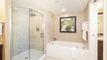 A modern bathroom with a glass-enclosed shower, a freestanding bathtub, and a framed artwork on the wall.