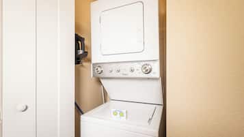 A compact washer and dryer unit with a control panel, a detergent box, and a small shelf above the dryer.