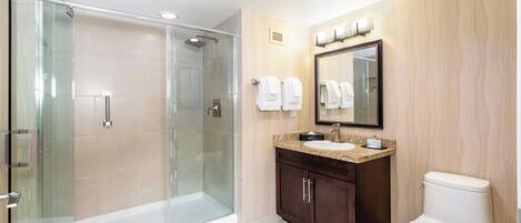 Un baño moderno con ducha de vidrio, lavabo con tocador y un inodoro.