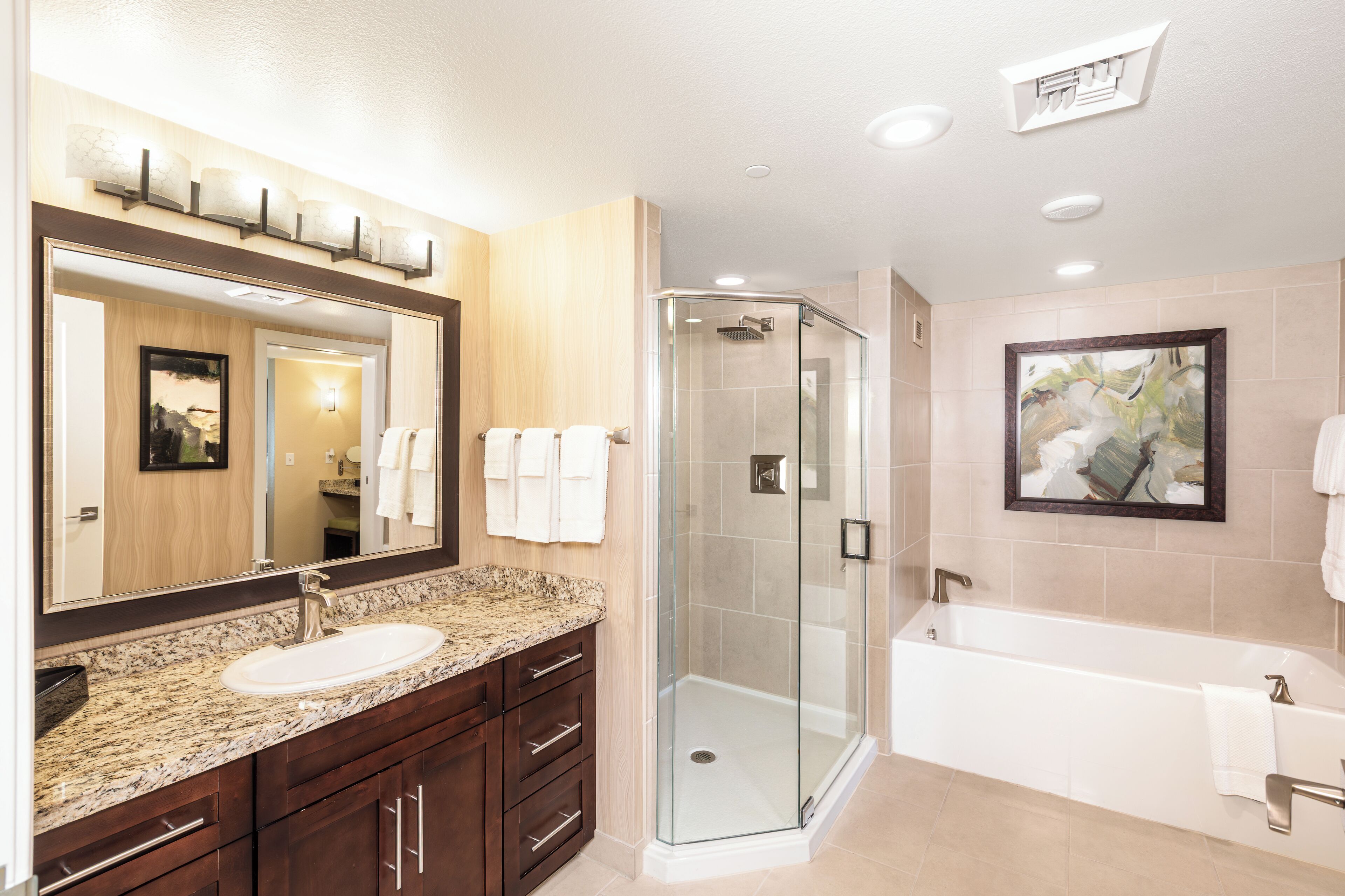 Une salle de bain moderne avec une douche à parois de verre, un grand miroir et une baignoire.