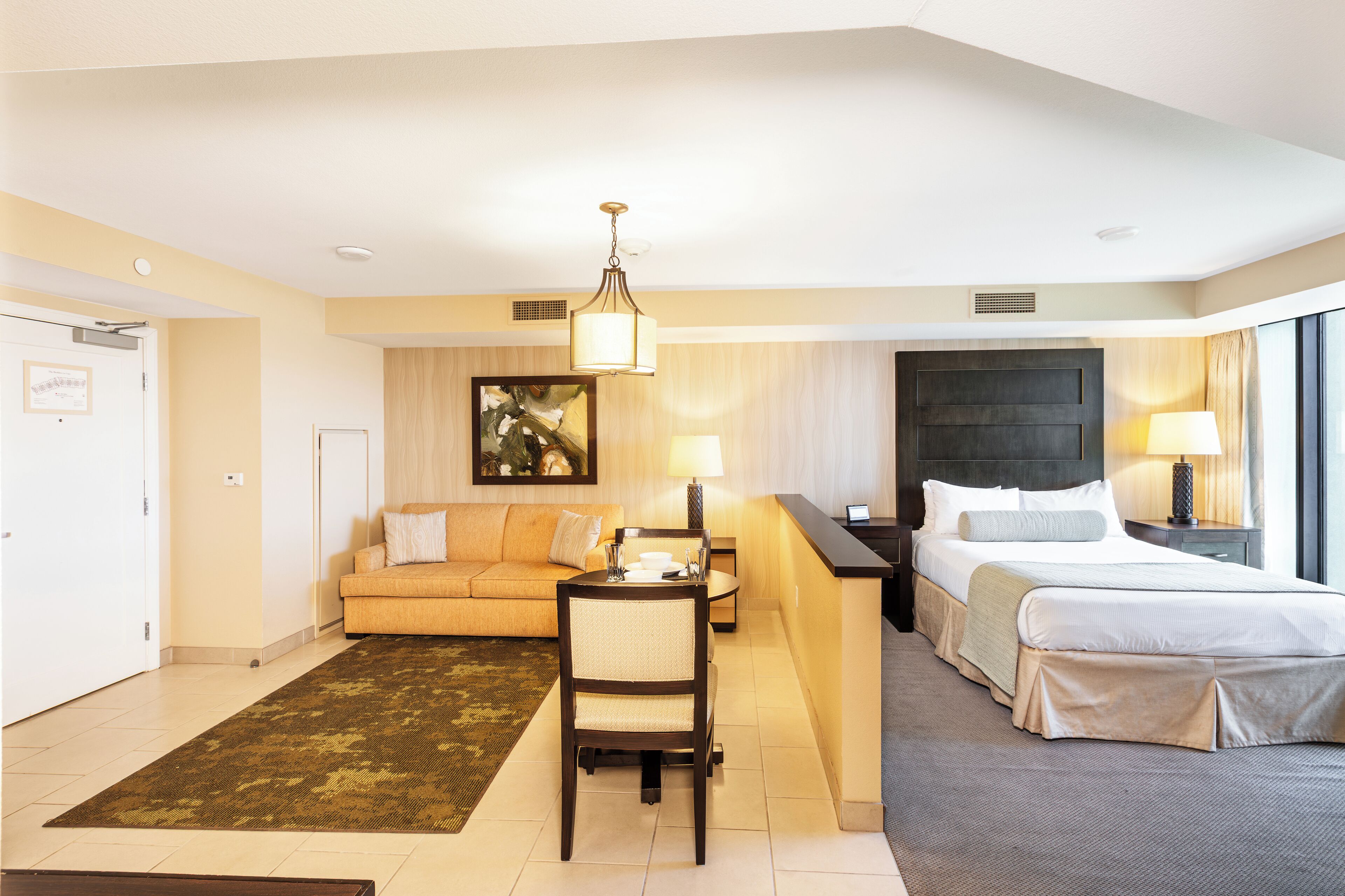 A hotel room with a bed, a sofa, a desk, and a chair.