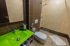 A bathroom with a green sink, a toilet, a shower, and a towel on the floor. - Lalla Doudja (Algiers)