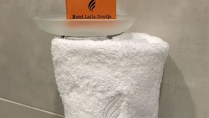 A white towel with an embossed design on a glass shelf above it.