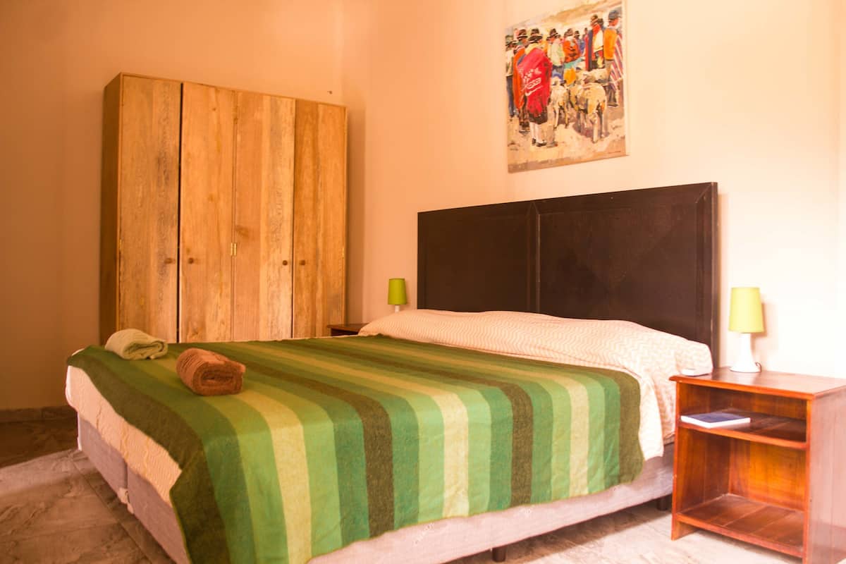 Une chambre à coucher avec un lit, une armoire en bois, des tables de chevet et un tableau au mur.