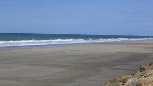 Una playa con costa rocosa y olas acercándose a la orilla.
