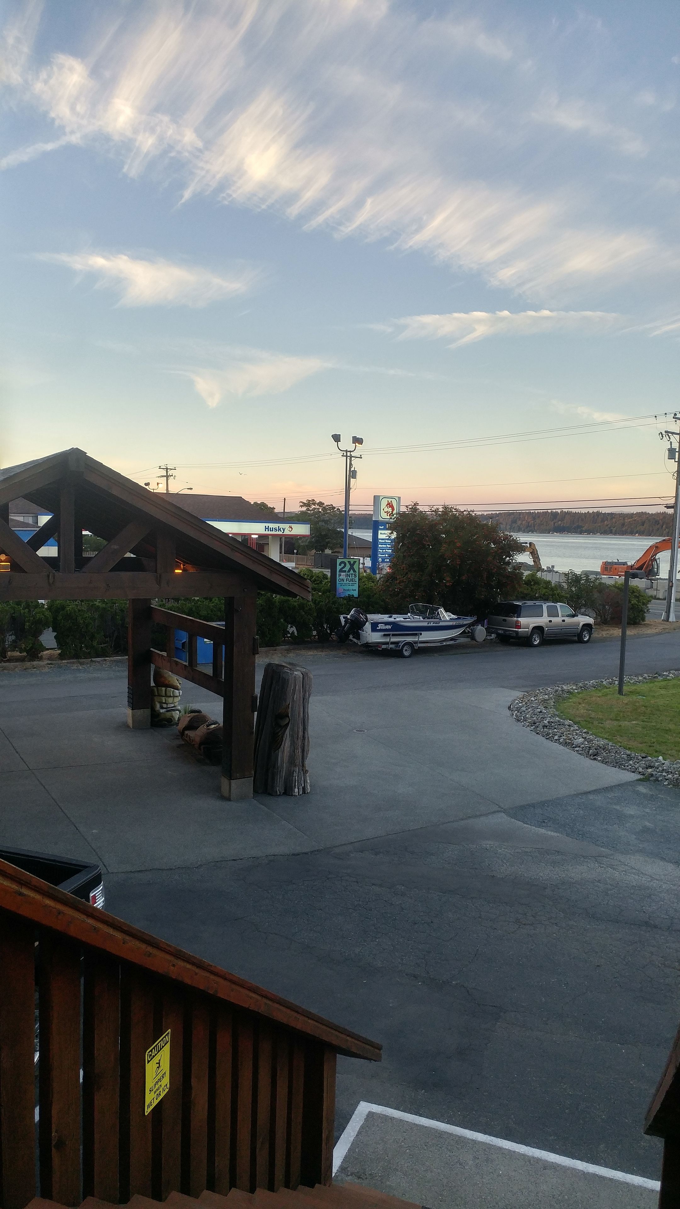 A parking area with a boat, a Husky gas station, and a bridge in the background.