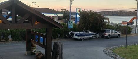 A parking area with a boat, a Husky gas station, and a bridge in the background.