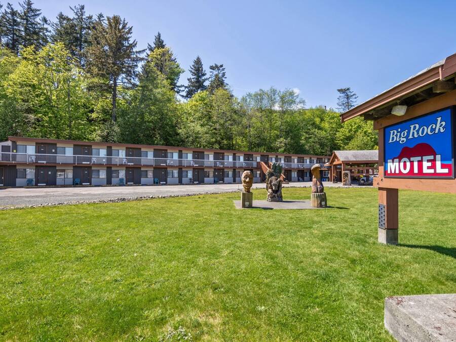 Un motel avec une enseigne indiquant « Big Rock Motel », un parking et une zone herbeuse agrémentée d’une statue.