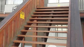 A wooden staircase leading to a building with a caution sign.