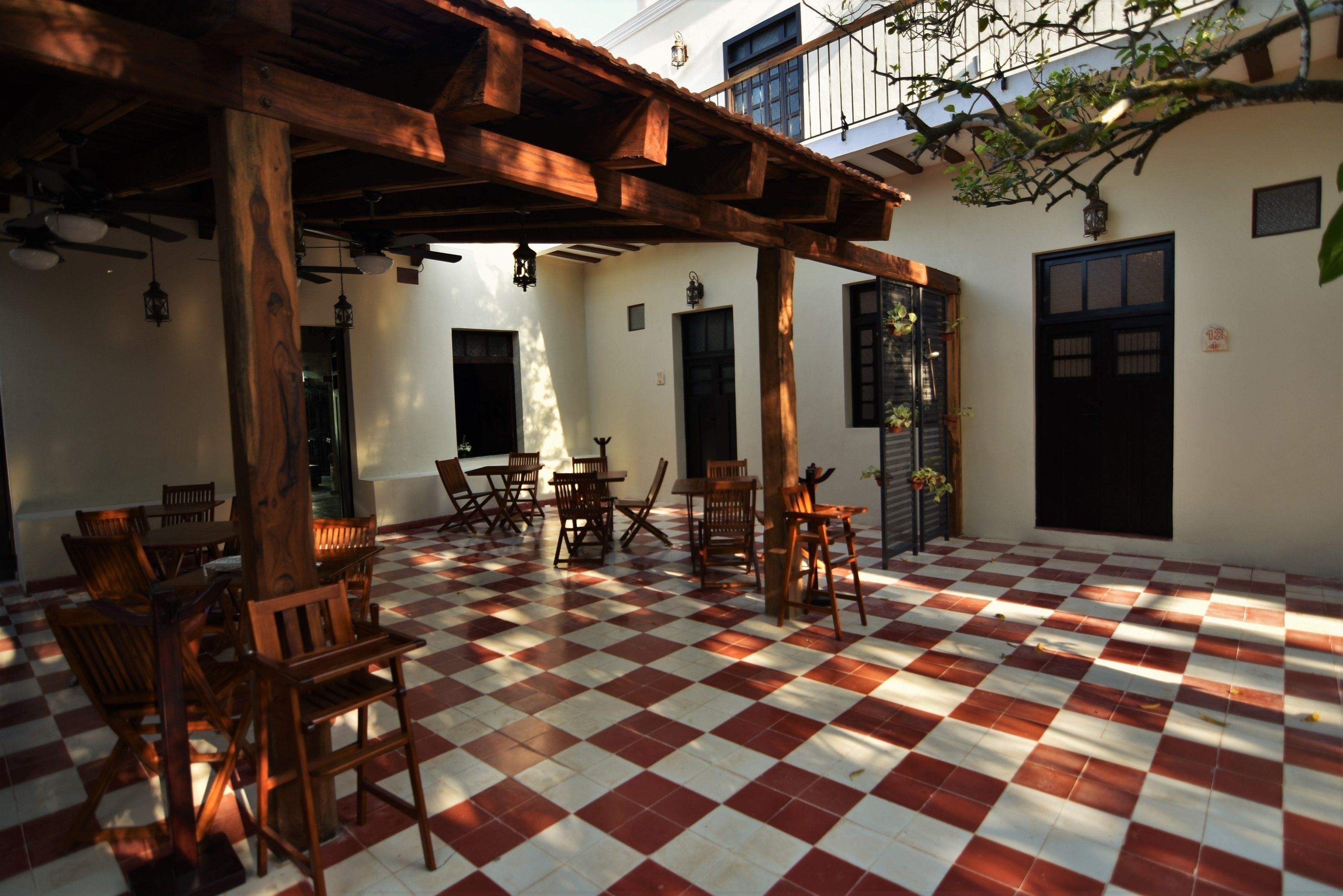 Un patio con suelo a cuadros, mobiliario de madera y una pérgola de madera.