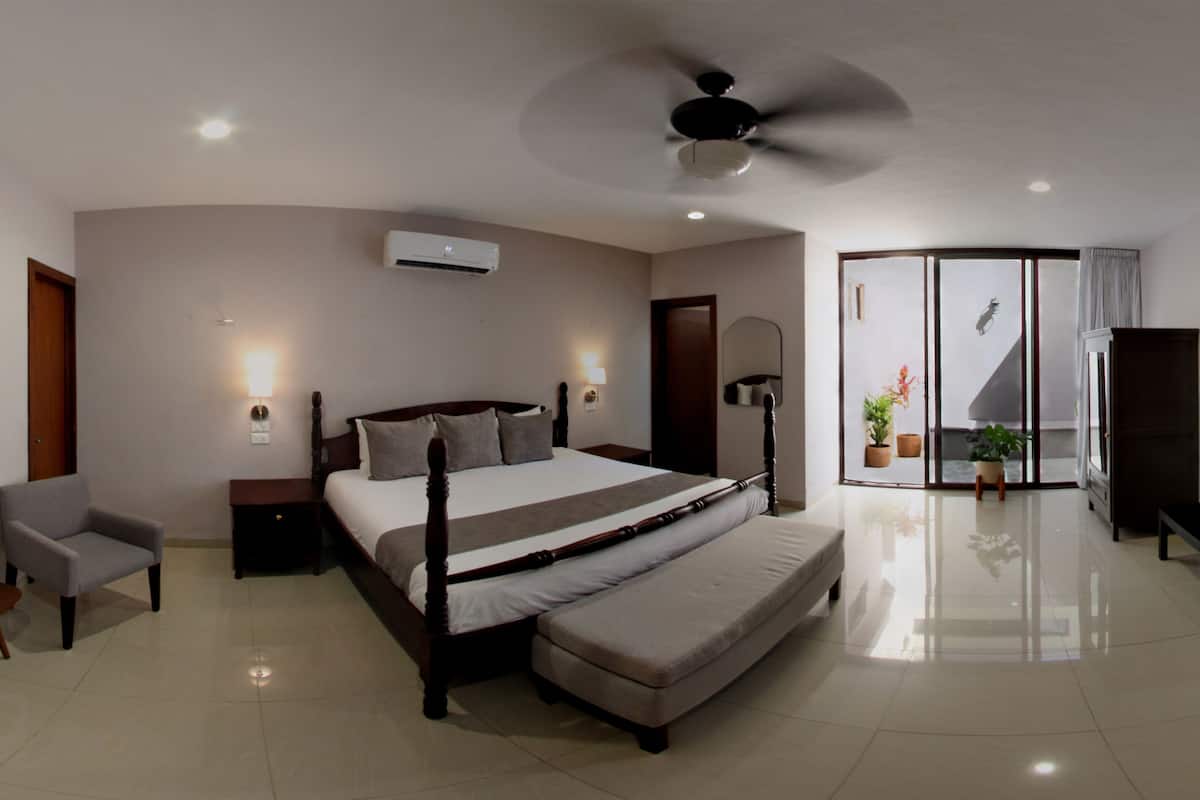 Ein modernes Schlafzimmer mit einem großen Bett, einem Deckenventilator und einer Glastür, die auf einen Balkon führt.