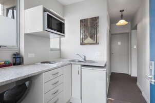 A modern kitchen with a built-in microwave, a sink, and a painting of a forest.