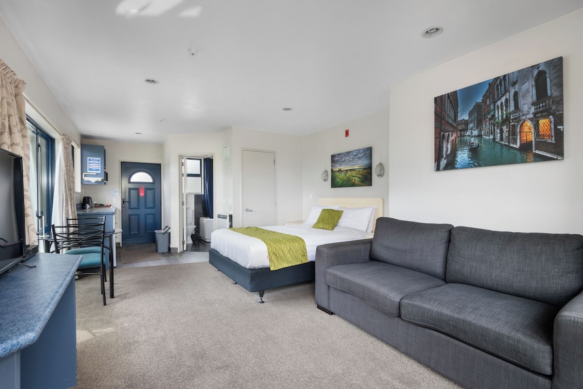 Ein Hotelzimmer mit Bett, Sofa, Schreibtisch und Bad.