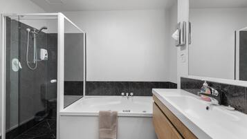 Une salle de bain moderne dotée d’une douche à parois de verre, d’une baignoire sur pieds et d’un meuble-lavabo avec un miroir.