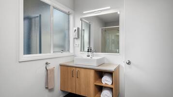 Une salle de bain moderne avec un lavabo blanc, un meuble en bois et un grand miroir.
