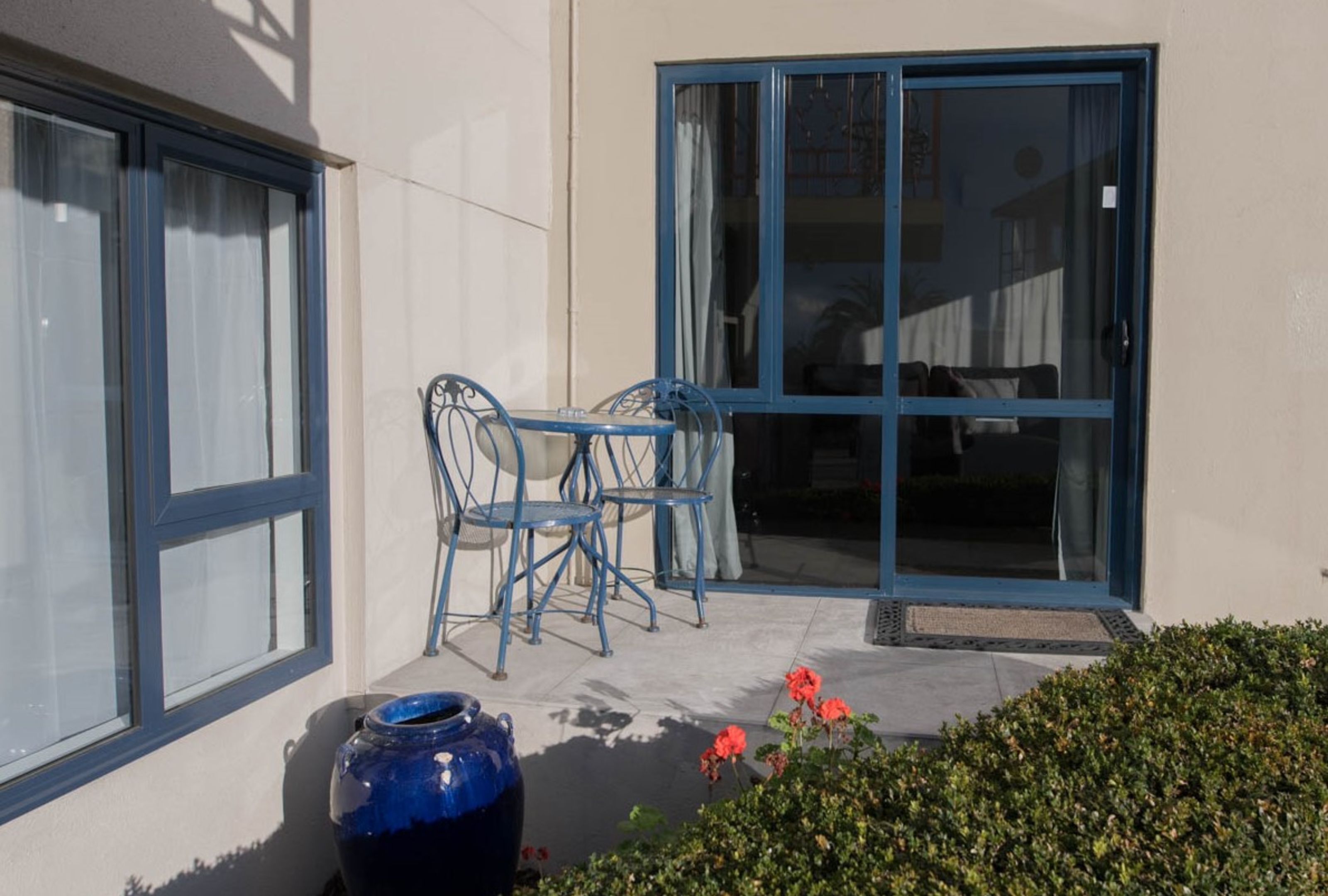 A patio with a table and chairs, a large vase, and a door with glass panels.