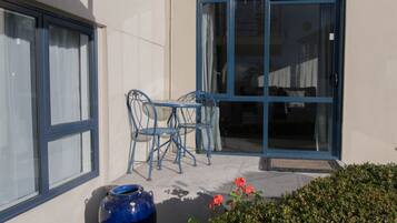 A patio with a table and chairs, a large vase, and a door with glass panels.