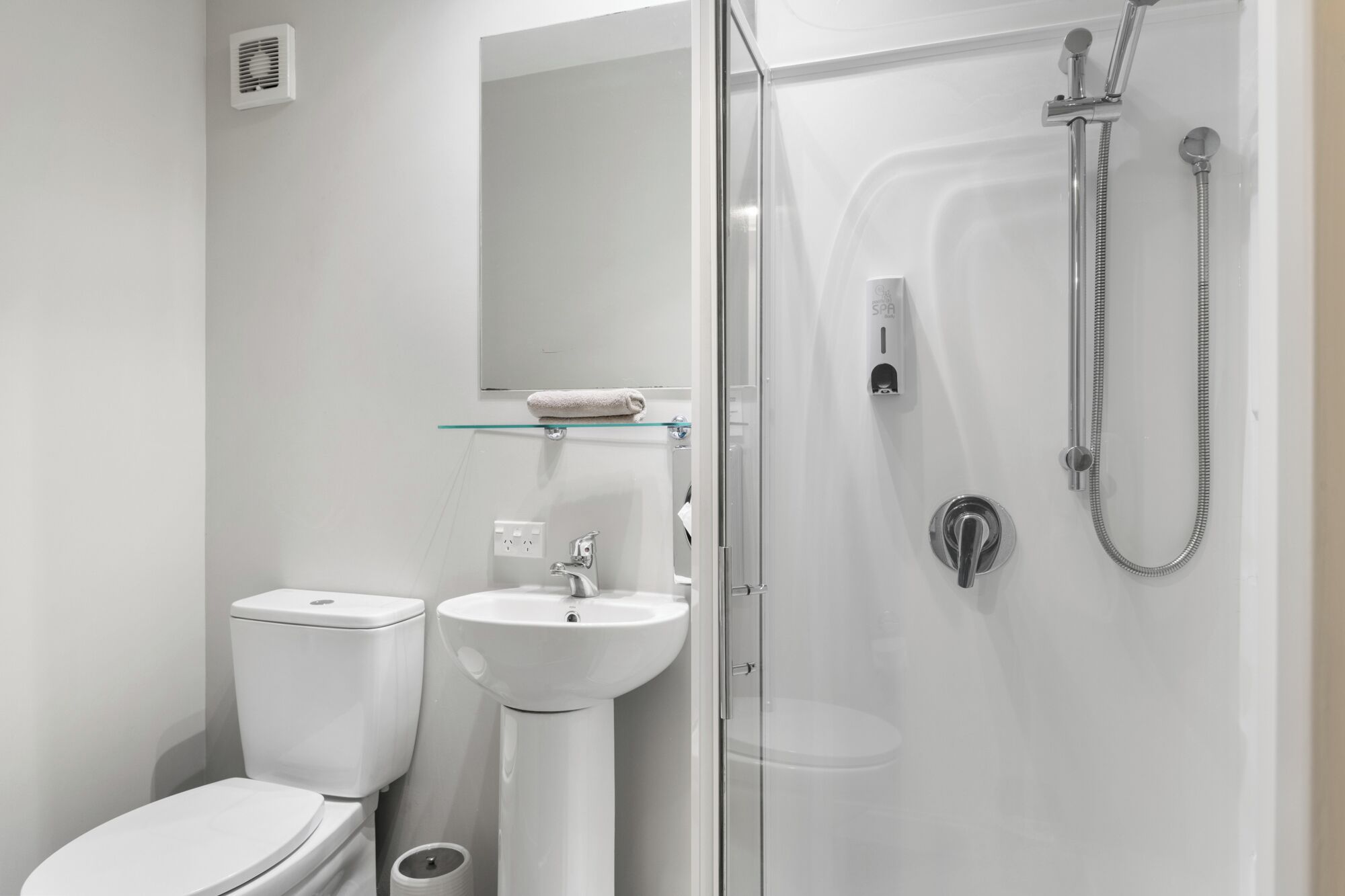 A modern bathroom with a toilet, sink, and glass-enclosed shower.