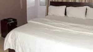 Une chambre d’hôtel avec un grand lit, un téléviseur fixé au mur et un rideau à motifs.