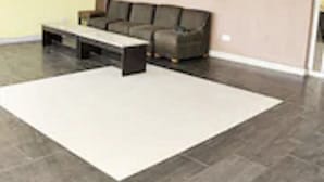 Un salon moderne avec un canapé gris, une table basse blanche et un grand tapis blanc.