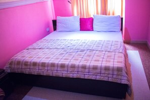 Un lit avec une couvre-lit à carreaux, deux oreillers et une fenêtre avec des rideaux.