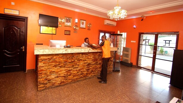 A reception area with a stone counter, a chandelier, and a sign indicating a staff-only area. - Trafford Hotel (Abuja)
