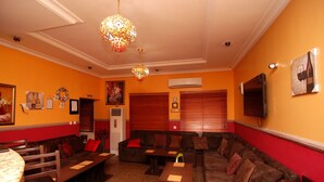 A cozy lounge area with a sofa, chairs, and tables, featuring a chandelier and artwork on the walls. - Trafford Hotel (Abuja)