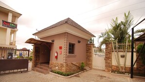 A small building with a stone facade, a tiled roof, and a gated entrance. - Trafford Hotel (Abuja)