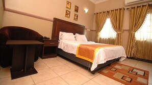 A hotel room with a bed, a desk, and a chair. - Trafford Hotel (Abuja)