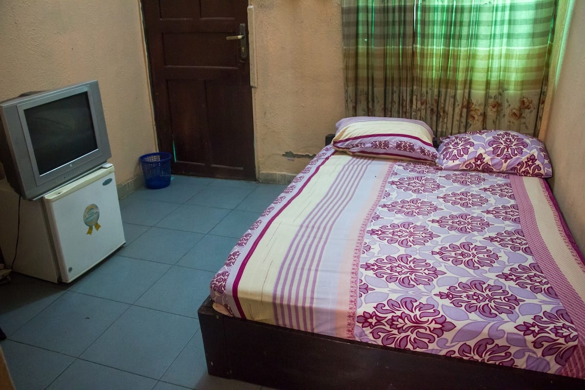 Ein Schlafzimmer mit einem Bett, einem Fernseher und einem kleinen Kühlschrank.