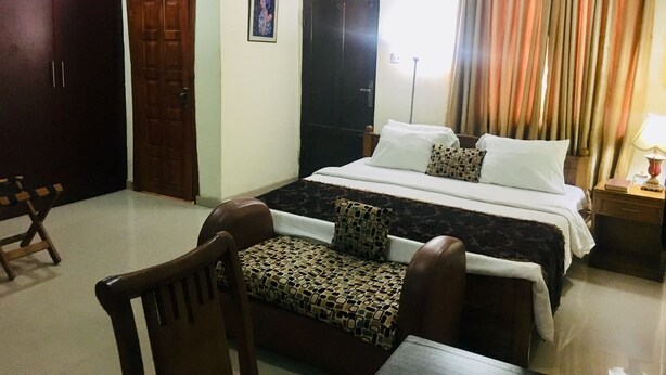 Una habitación de hotel con una cama, una silla, un armario y una puerta.