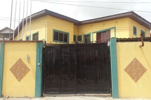 A yellow building with a black gate and green trim.