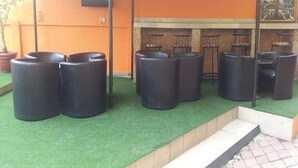 A seating area with black chairs and a small step leading to a brick wall. - Peerage Retreat and Resort (Lagos)