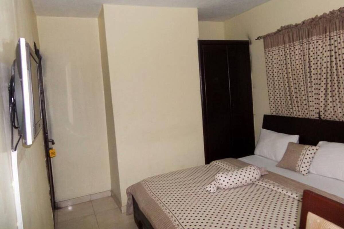 A bedroom with a bed, a wardrobe, a television, and a curtain.