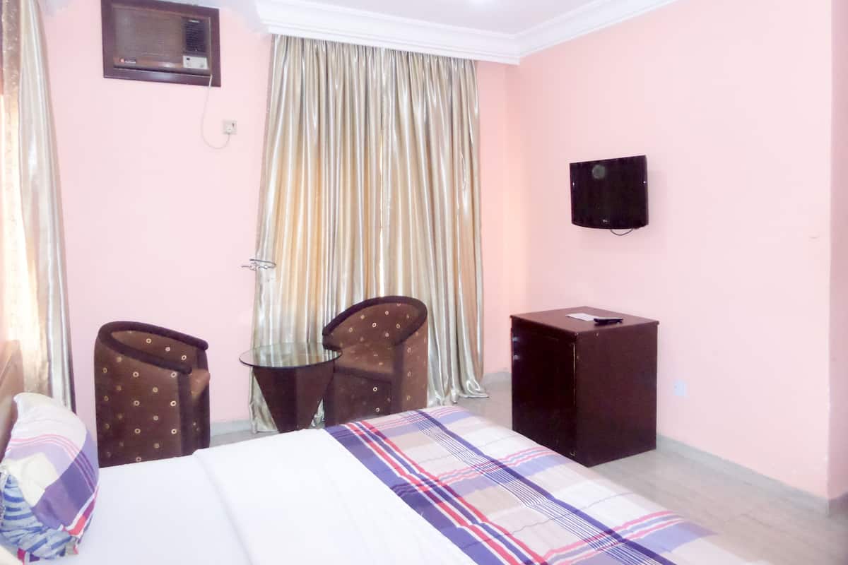 A hotel room with a bed, a desk, a chair, a television, and curtains.