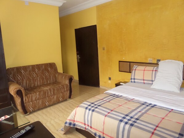 A hotel room with a bed, a sofa, and a TV.
