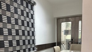 A modern kitchen with a granite countertop, a window with a checkered blind, and a view of the outside. - Foramot Suite (Lagos)