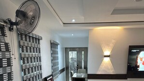 A modern conference room with a long table, comfortable chairs, a wall-mounted fan, and a TV screen. - Foramot Suite (Lagos)