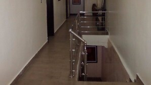 A narrow hallway with a staircase leading to an upper floor. The walls are plain with minimal decoration. - Foramot Suite (Lagos)