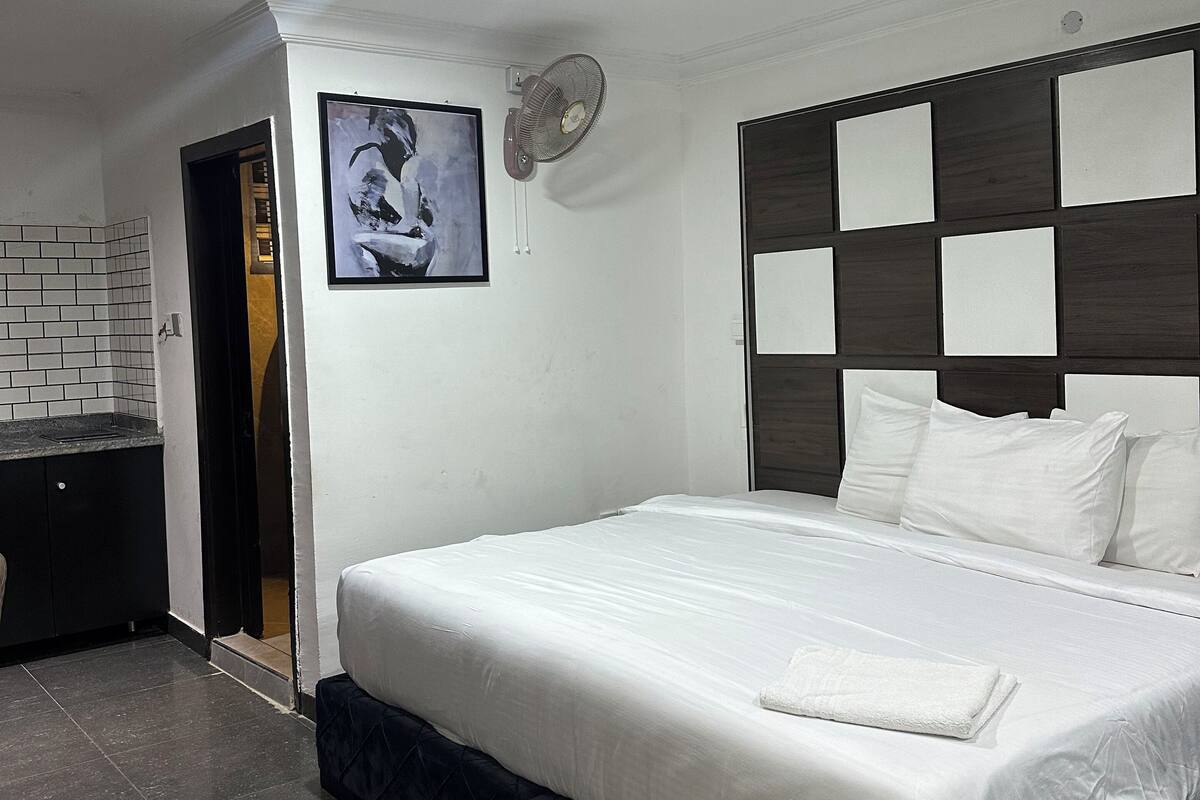 A modern bedroom with a large bed, a built-in desk, and a ceiling fan.