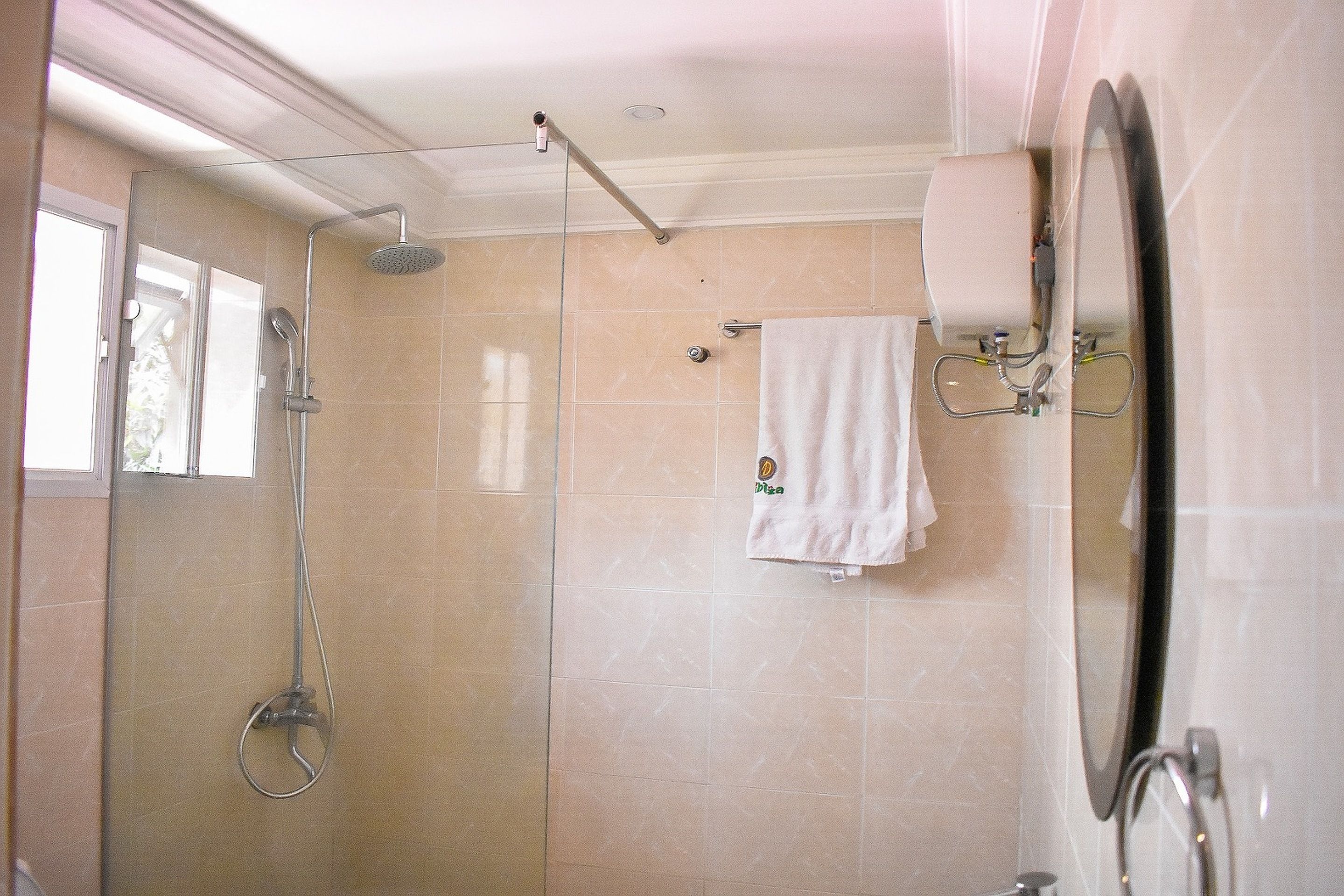 A bathroom with a glass-enclosed shower, a towel hanging on the wall, and a mirror.