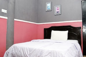 A bedroom with a bed, a black headboard, and two framed pictures on the wall.