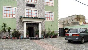 A building with a stone facade, multiple windows, and a parked car in front. - Royal Park Hotel & Suites (Lekki)