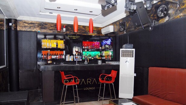 A bar area with a black counter, red chairs, and a red couch. - Royal Park Hotel & Suites (Lekki)