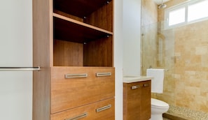 A bathroom with a wooden vanity, a glass shower enclosure, and a tiled shower floor.