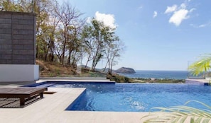 A swimming pool with a view of the ocean and hills.