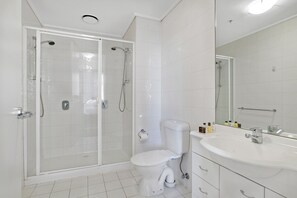A modern bathroom with a glass-enclosed shower, a white toilet, and a vanity with a mirror. - Premier stays (Southbank)