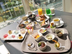 A table with various dishes and drinks, including a croissant, fruit, and a glass of orange juice. - Piazza Hotel Nara (Nara)